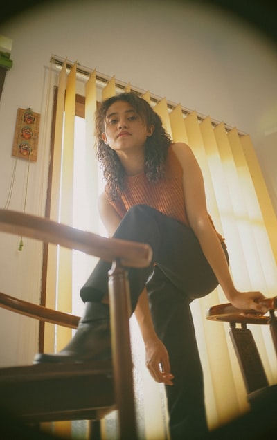 穿着黑色背心和黑色裤子的女人坐在棕色木椅上